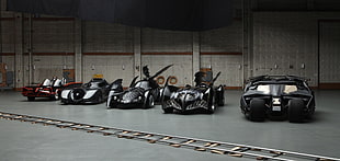 four black and one brown batmobiles parked on gray building