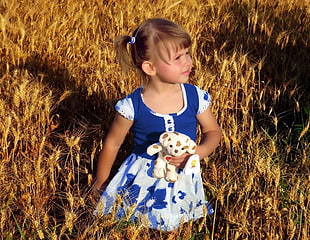 photo of kid in blue and white dress on brown wheat field during day time