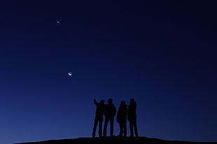 four people standing on top of the hill during nighttime