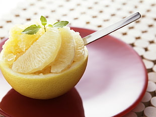 sliced orange with spoon on round red plate
