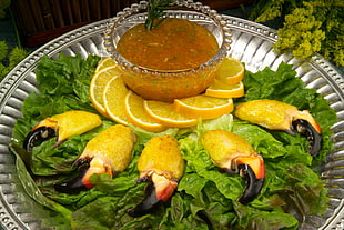 cooked crab claws with sliced lemons and sauce