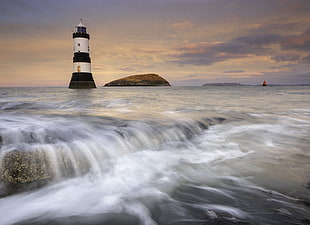 time lapse photography of white lighthouse near sea during daytime