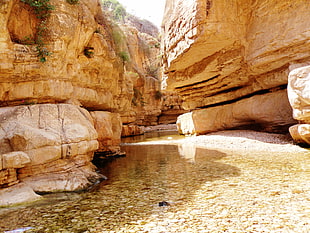 body of water between beige rock formation