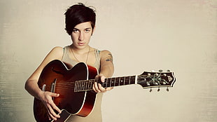 woman in brown tank-top holding brown acoustic guitar