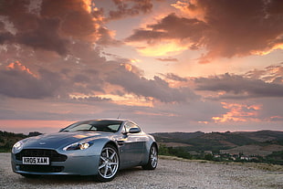 silver Aston Martin coupe under cloudy blue sky