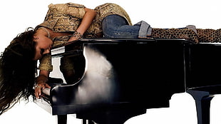woman wearing brown top and blue denim capris lying on black grand piano