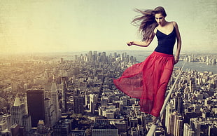 woman wearing black and red tank dress walking on white bar above city skyline