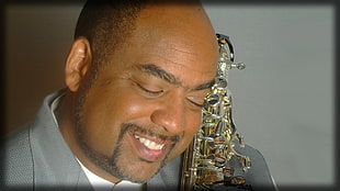 man in gray suit jacket carrying saxophone