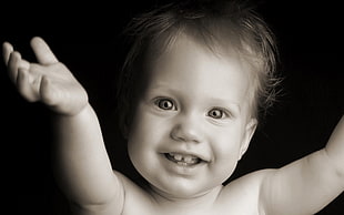 toddler raising his arms while smiling