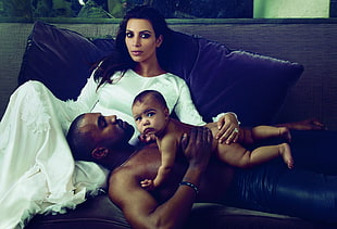 Kanye West, Kim Kardashian, and North West laying on black leather couch
