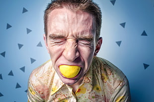 man in floral shirt with lemon in mouth