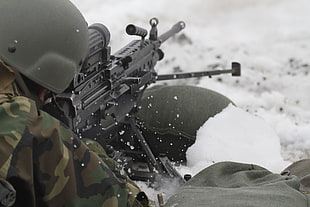 soldier in camouflage uniform holding rifle during snow