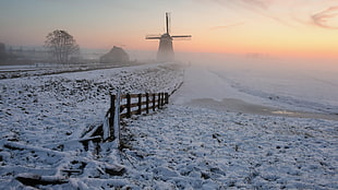 silhouette of windmill surrounded by white snow during sunset