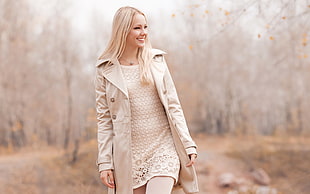 selective focus photography of woman in beige coat holding bag in the middle of trees HD wallpaper