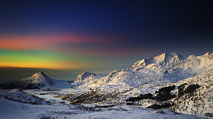 snow coated mountain during multicolored sunset