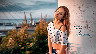 woman wearing white and black star print crop top with black bra beside white white concrete wall