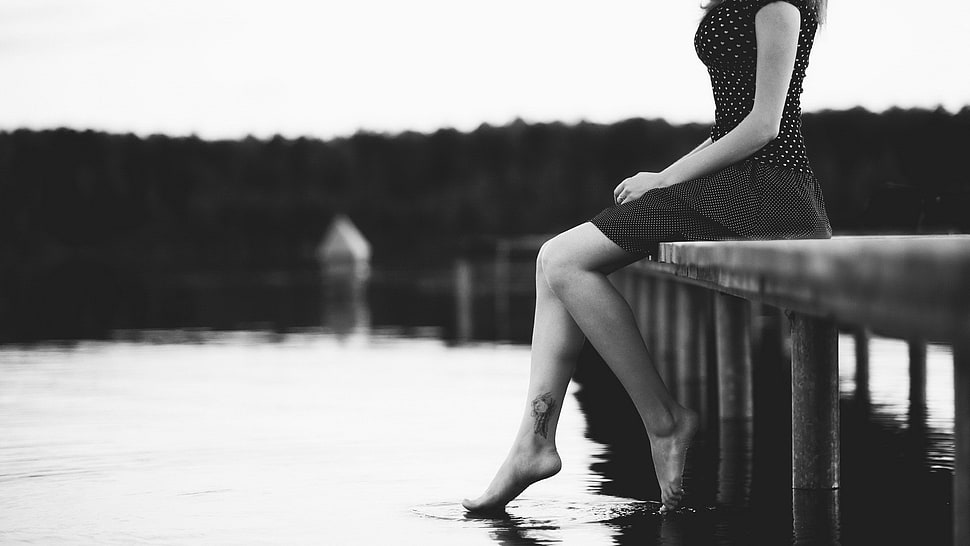 grayscale photo of woman in black skater dress sitting on dock bridge HD wallpaper