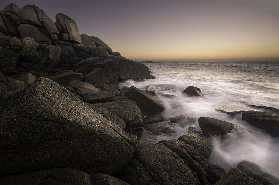 rocks near the seashore during golden hour HD wallpaper