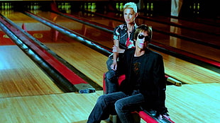 man in black jacket with woman in black and white top sitting on bowling alley