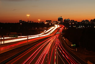 time-lapse photography of vehicle running on road near buildings at golden hour, highway 401, don mills