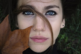 woman's close up photography with dried leaves on face
