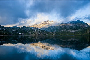 reflection photography of mountains under white clouds