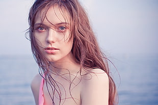 portrait photography of brown haired woman behind body of water during daytime