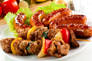 sausage and barbecue served on white ceramic plate with lettuce