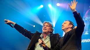 two men singing on a stage