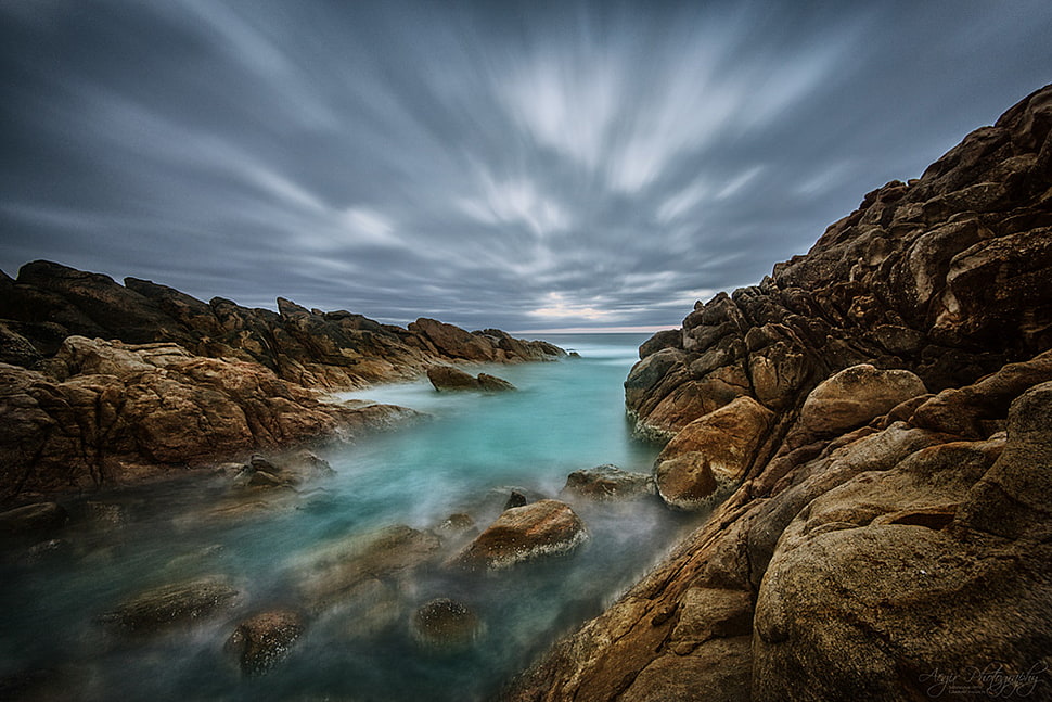 river surrounded by brown rock formation under cloudy sky HD wallpaper