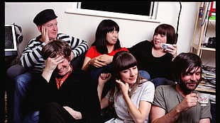 group of people sitting on chair near white wall paint