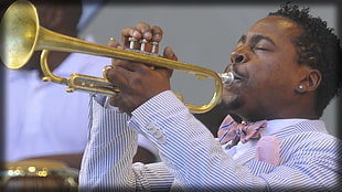 man in white and black striped collared shirt playing trumpet