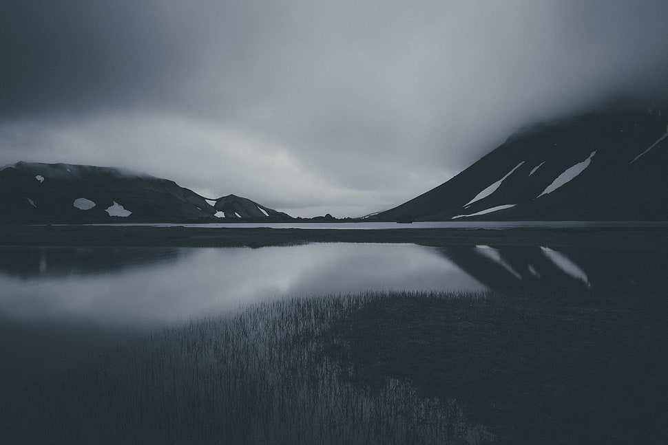 grayscale photo of body of water near mountain HD wallpaper