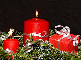 red pillar candle beside gift box