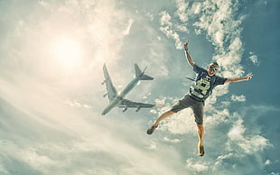 man wearing crew-neck t-shirt and gray shorts, landscape, jumping, airplane, sky
