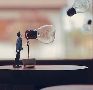 forced perspective photo of man standing in front of light bulb, digital art, men, lightbulb