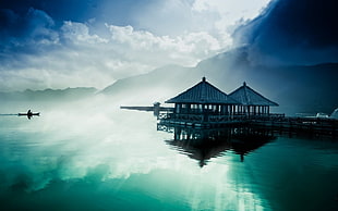 two wooden cottages near a blue water and mountain
