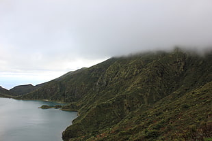 mountain beside a body of water under grey clouds, lagoa, fogo, azores, portugal