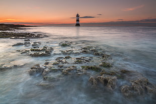 Lighthouse on body of water surrounded stones, penmon HD wallpaper