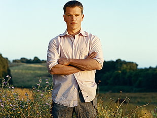 Matt Damon in white dress shirt standing on green lawn during daytime