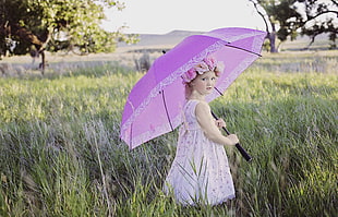 girl on grass field with umbrella during daytime