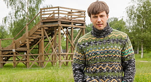 man in green sweater standing behind brown wooden park slide HD wallpaper
