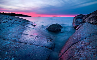 landscape photography of seashore with giant stones under pink and blue sky during daytime HD wallpaper
