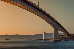 bridge near lighthouse under clear white sky HD wallpaper