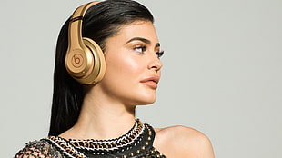 woman wearing gold-colored Beats By Dr. Dre wireless headphones