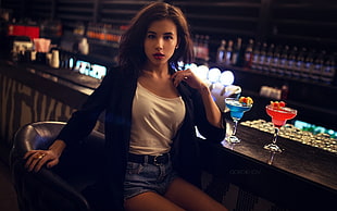 woman wearing white top sitting on bar stool