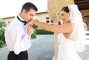man in white dress shirt kissing woman's left hand