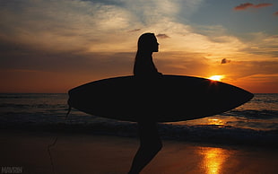 silhouette photo of person holding surfboard