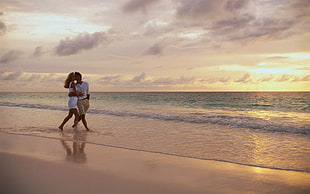 couple walking on seashore during sunset