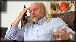 photo of man wearing gray dress shirt holding drinking glass